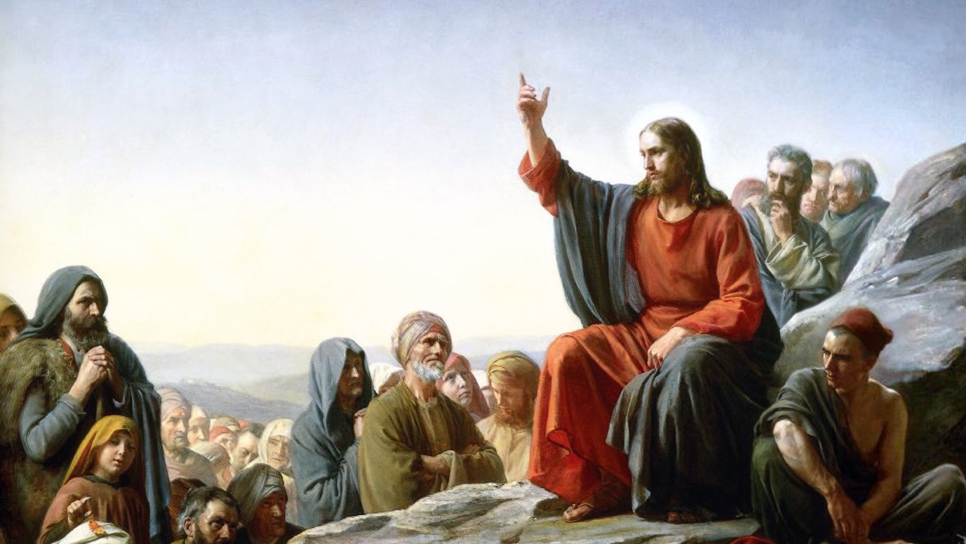 Jesus sitzt auf einem Felsen, eine Hand erhoben, und lehrt eine Menschenmenge, die sich an einem Hang versammelt hat.